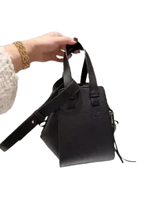 Close-up of a hand holding a Mini Loewe Puzzle Bag in smooth leather, showcasing the top handle, embossed Anagram logo, and crossbody strap.