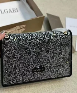 Bvlgari luxury shoulder bag, heavily embellished with crystals or rhinestones on a black background.
