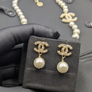 Detailed view of a graduated pearl necklace and drop earrings set, showcasing the intricate rhinestone embellishment on the signature interlocking C logo.
