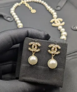 Detailed view of a graduated pearl necklace and drop earrings set, showcasing the intricate rhinestone embellishment on the signature interlocking C logo.