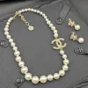 Overhead product image of the full matching set, including the gold-tone, crystal-embellished CC earrings standing next to the long pearl necklace.