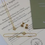 Gold clover necklace, bracelet and earrings displayed on authenticity papers