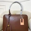 A Miu Miu leather tote bag with embossed logo and braided handle detail placed on a cushioned chair.