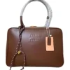 A Miu Miu leather tote bag with embossed logo and braided handle detail placed on a cushioned chair.