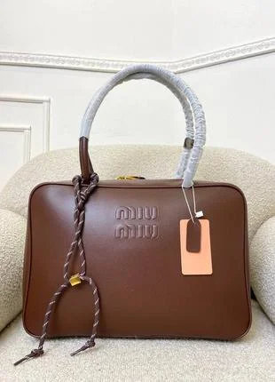 Miu Miu Luxury Leather Tote Bag A Miu Miu leather tote bag with embossed logo and braided handle detail placed on a cushioned chair.
