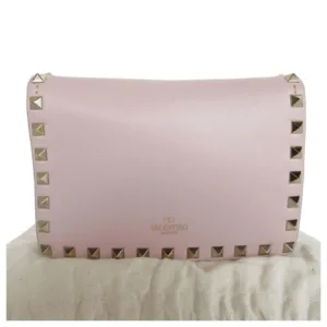 Close-up front view of light pink Valentino Garavani Rockstud leather shoulder bag with gold-tone pyramid studs and logo stamp.