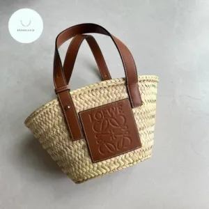 Full view of the artisan-made basket bag, showcasing the intricate woven raffia body and the smooth leather top handles.