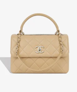 Small quilted Chanel bag in light brown leather with gold hardware and top handle.