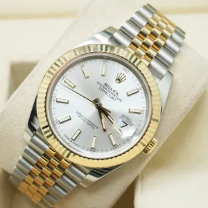 Close-up of a two-tone Rolex Datejust 41 with a silver dial, 18k yellow gold fluted bezel, and steel and gold Jubilee bracelet on a watch cushion.