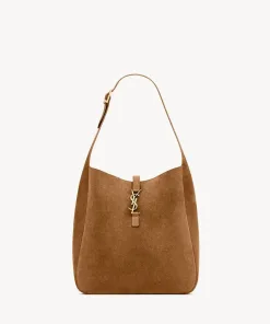 Tan suede hobo shoulder bag featuring the iconic large antique gold-toned YSL Cassandre logo on the front.