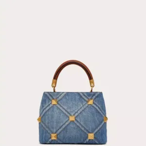 Front view of the Small Valentino Garavani Roman Stud Handle Bag in quilted denim with contrasting stitching and antique brass maxi studs.