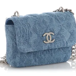 Compact light blue denim Chanel bag with a quilted or embossed pattern.