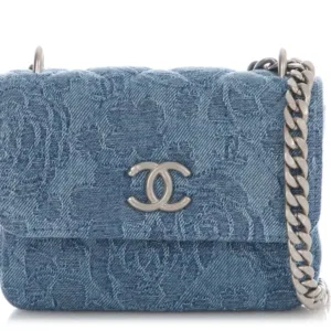 Chanel small flap bag in blue denim with subtle floral embossing and silver chain strap.
