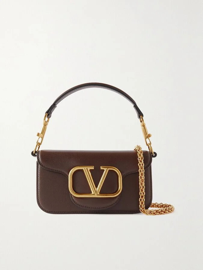 Detail of the convertible strap system on the Valentino leather bag, showing the top leather shoulder strap and the long detachable gold chain strap