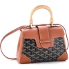 Front view of a rigid, structured handbag (Goyard Saïgon style) featuring a signature chevron/Y-pattern, wooden top handle, and corner reinforcements.