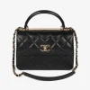 Small quilted Chanel bag in black leather with gold hardware and top handle.