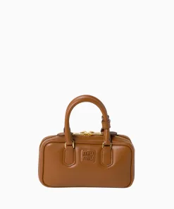 Close-up of a Miu Miu mini leather box handbag featuring gold zippers and top handles.