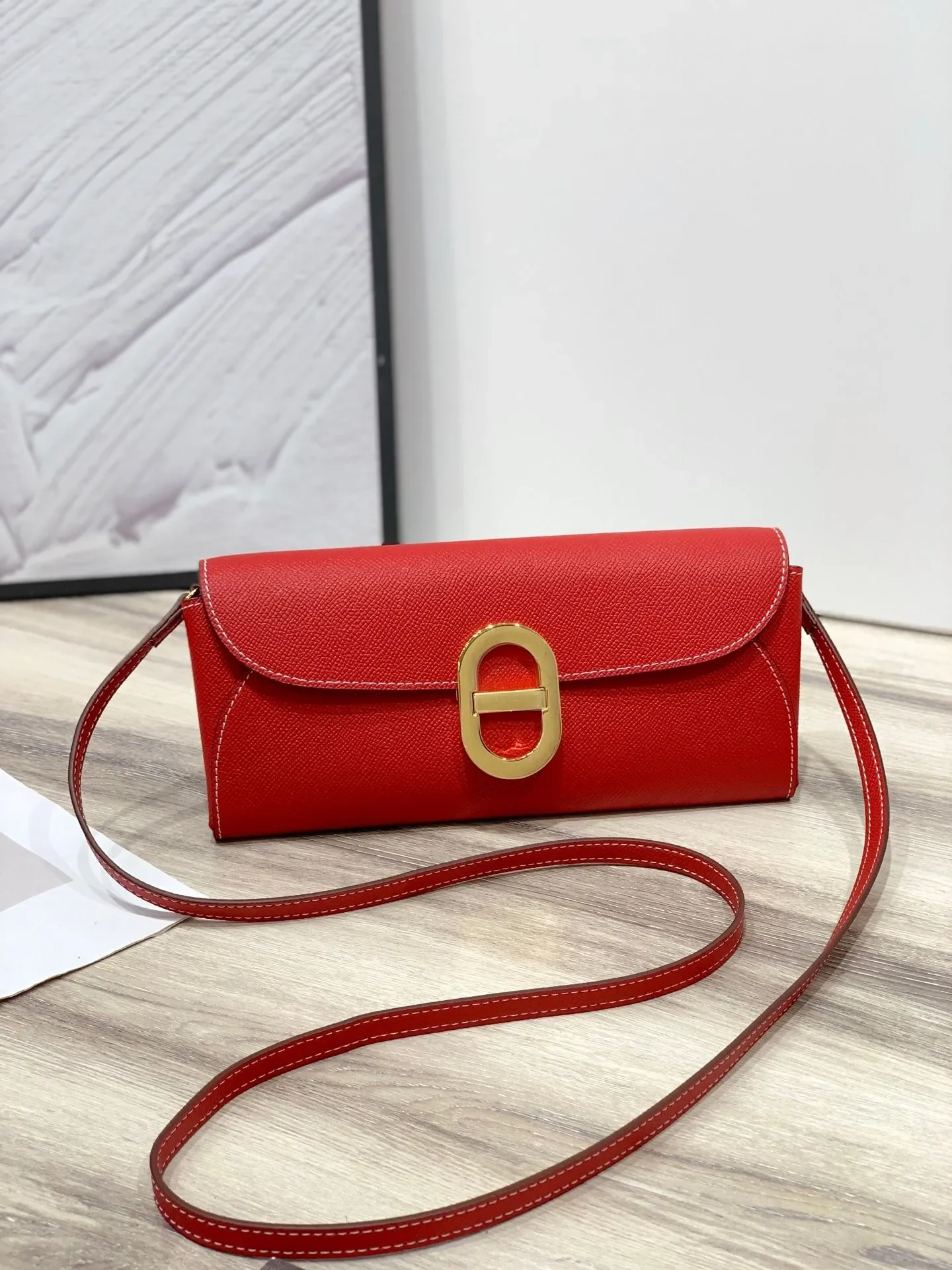 Epsom calfskin long wallet worn crossbody using its removable strap, highlighting its structured shape and firm hand.