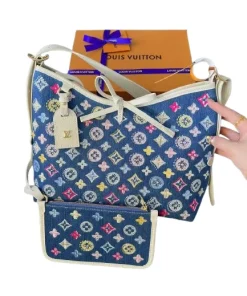 Louis Vuitton CarryAll MM in Monogram canvas on a desk with laptop, wallet, and sunglasses, lifestyle view