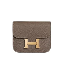 Side view of Hermès Constance Slim Wallet in warm taupe showing removable zippered change purse and sleek leather finish