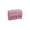 Luxury pink sequined Chanel flap bag shining under light, showing textured surface and elegant flap closure