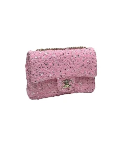 Luxury pink sequined Chanel flap bag shining under light, showing textured surface and elegant flap closure
