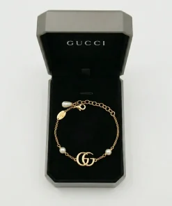 Gold Gucci GG Marmont bracelet with Double G logo and white glass pearl chain details