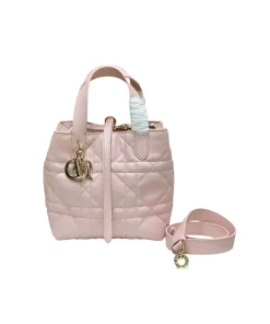 pastel pink luxury Dior tote handbag featuring quilted leather design and contrasting black leather handles.